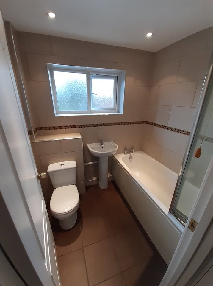 Completed bathroom with white suite and beige tiles