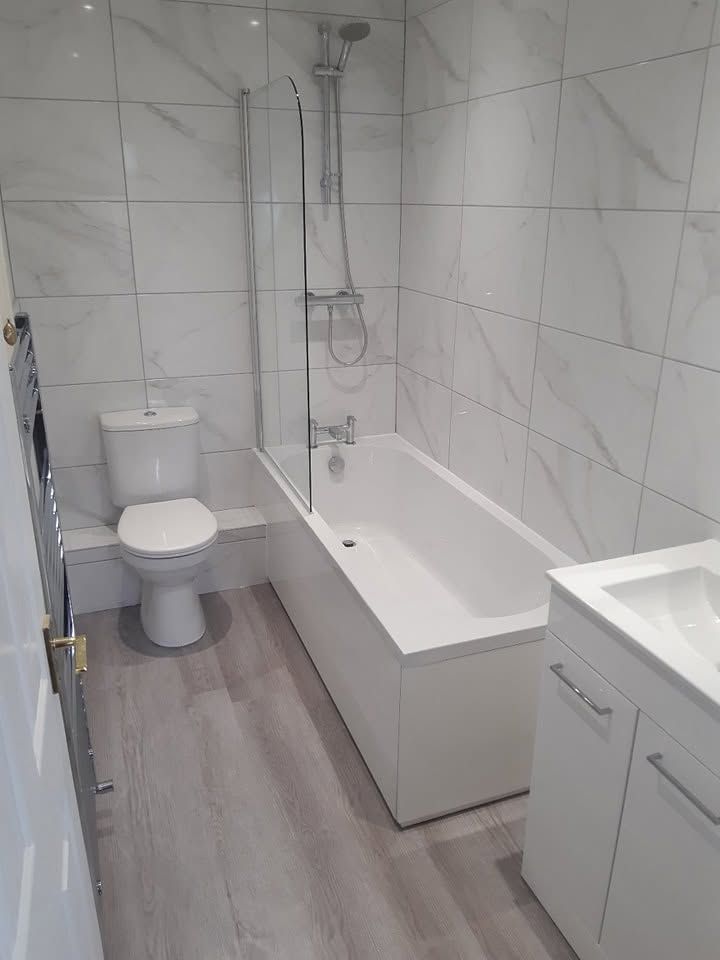 Bathroom after renovation with marble effect tiles and new white suite