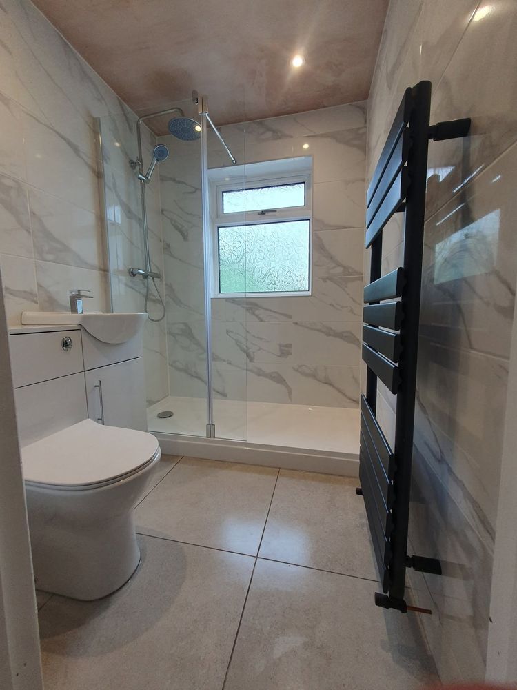 Walk-in shower with marble effect tiles and black heated towel rail