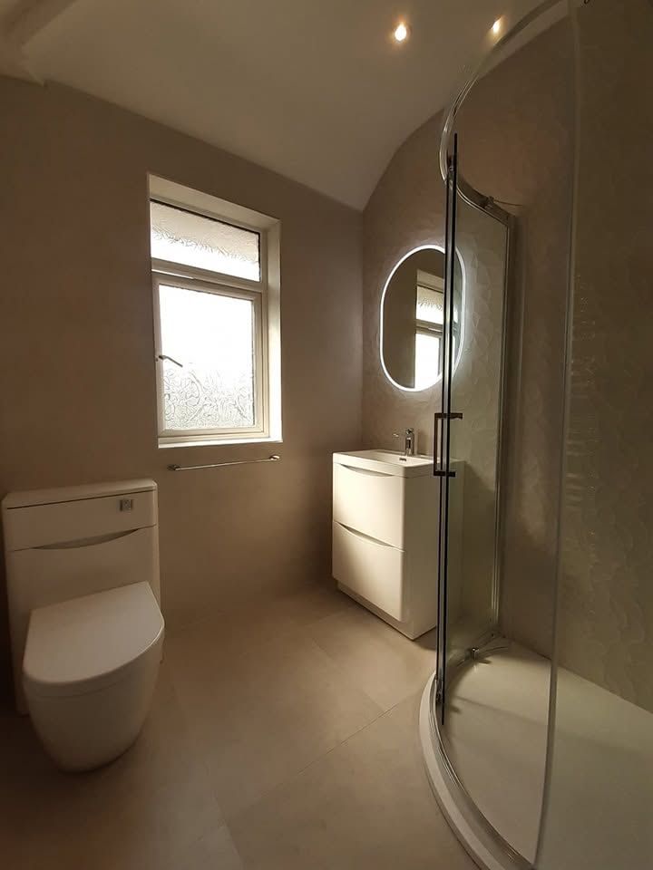 Modern bathroom with round illuminated mirror and curved shower