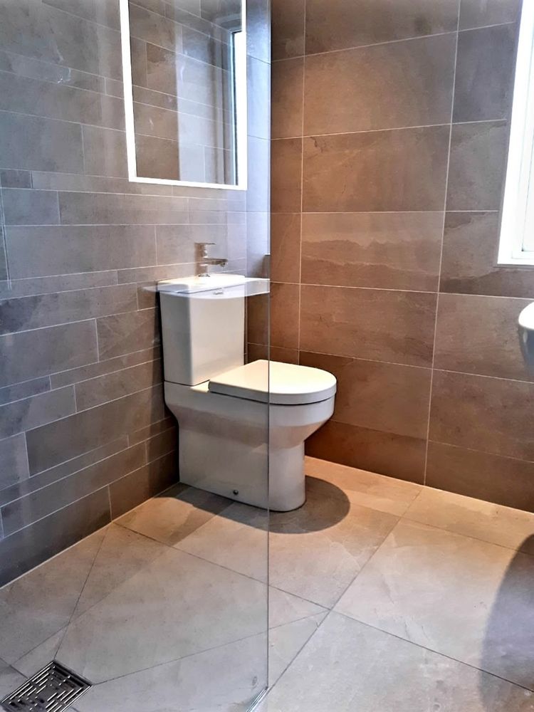 White shower room with tall storage unit and heated towel rail